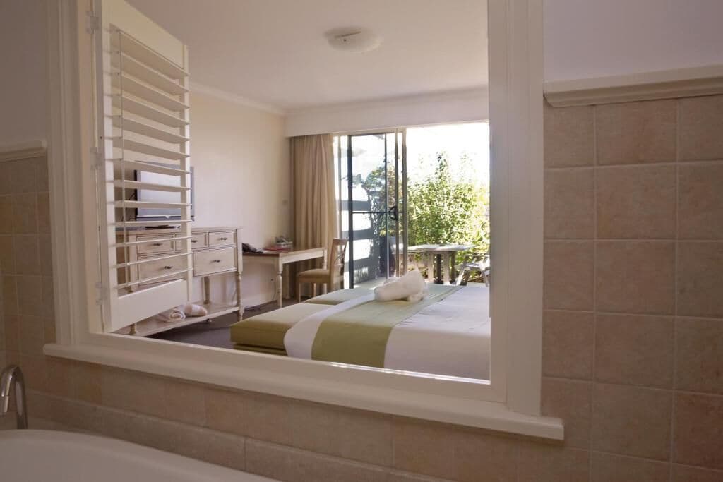 A hotel room with a bed, a desk, and a view of the outdoors.
