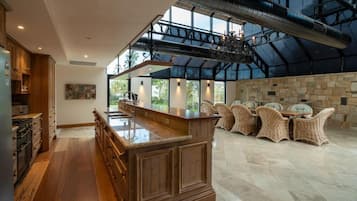Une cuisine spacieuse avec un îlot central, un coin repas avec des chaises en osier et un mur en pierre.