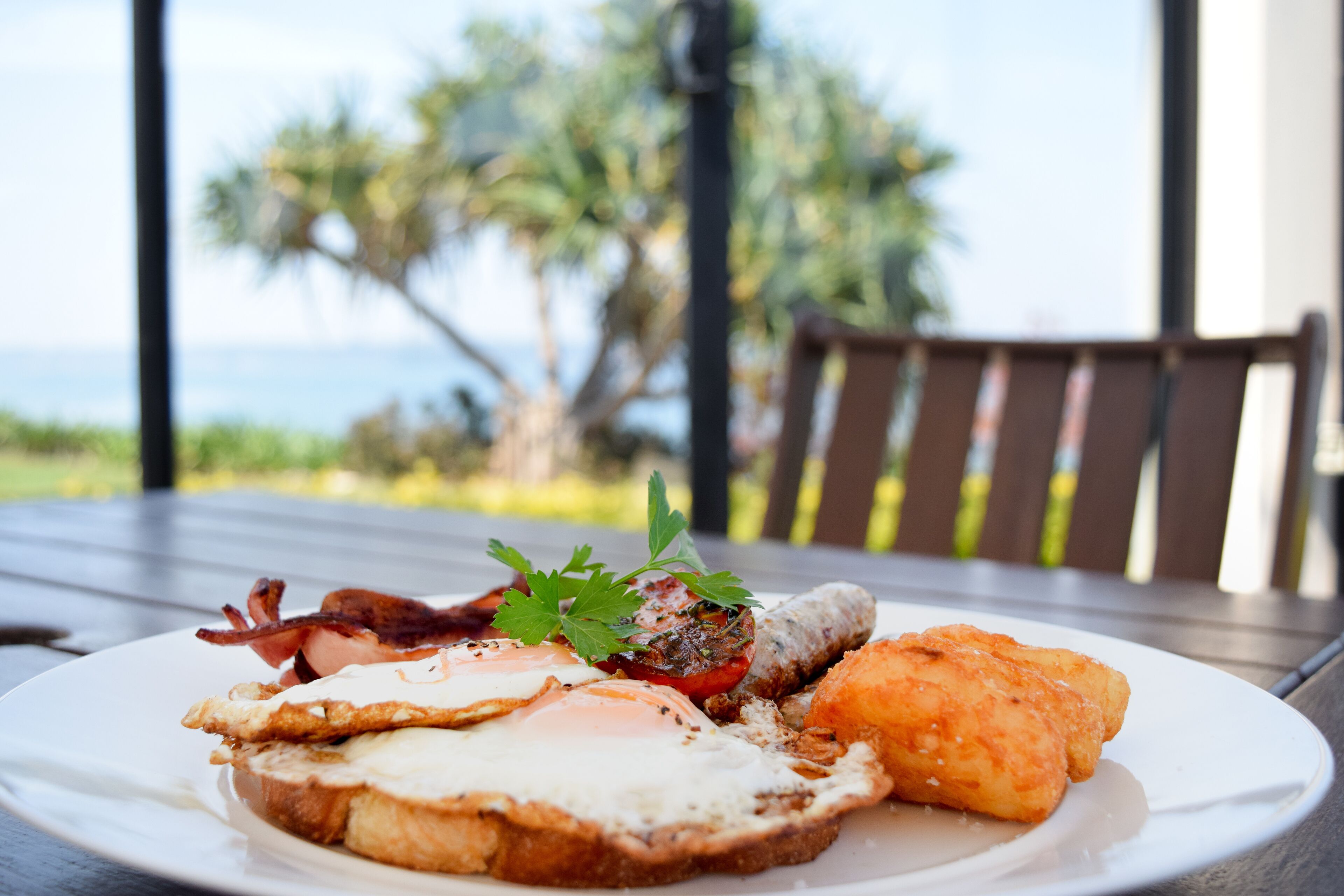 Een ontbijtbord met toast, ei, bacon, tomaat en gebakken aardappeltjes.
