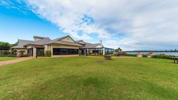 A large, modern house with a spacious lawn and a view of the water.