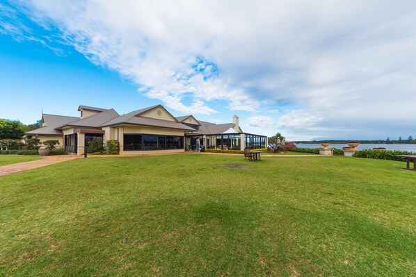 Una casa grande y moderna con un césped amplio y vistas al agua.