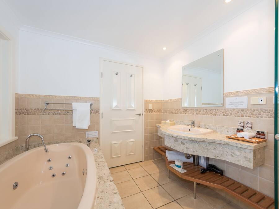 Un baño moderno con una bañera independiente, un lavabo doble y un espejo grande.