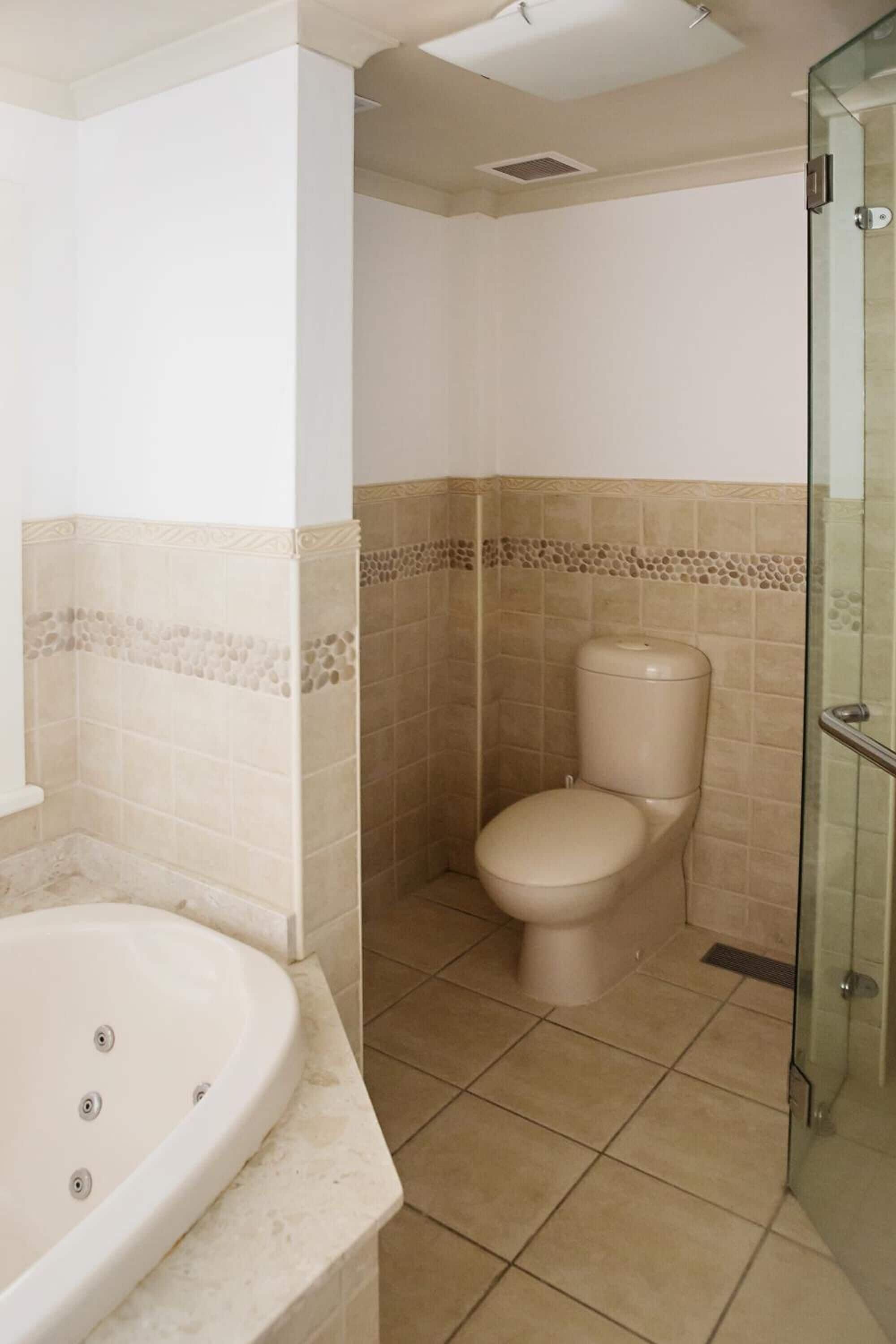 A bathroom with a bathtub, toilet, and glass shower enclosure.