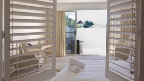 A hotel room with a bed, a small table, and a chair. There is a balcony with a glass door and curtains. - Harrington River Lodge (Harrington)