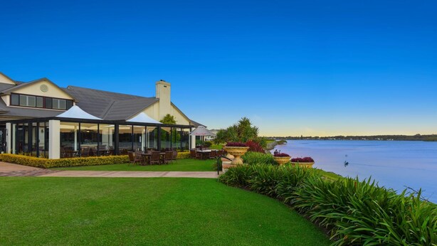 A waterfront hotel with a covered outdoor seating area, a well-maintained lawn, and a view of the water. - Harrington River Lodge (Harrington)