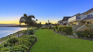 A coastal residential area with a well-maintained lawn, a palm tree, and houses with balconies overlooking the sea. - Harrington River Lodge (Harrington)