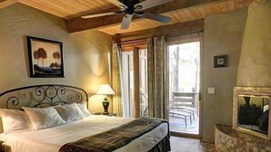 Ein Schlafzimmer mit einem Bett, einem Deckenventilator, einem Fenster und Blick ins Freie.