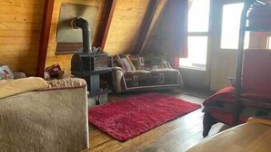 Una habitación estilo loft con techo de madera, chimenea, sofá y alfombra roja.