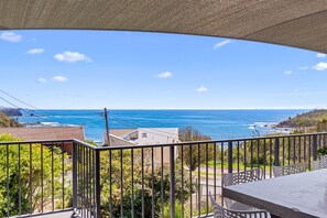 Ein Balkon mit Blick auf den Ozean, einem Tisch und Stühlen.