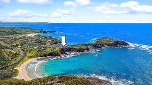 An aerial view of a coastal area with a beach, residential area, and a marked location.