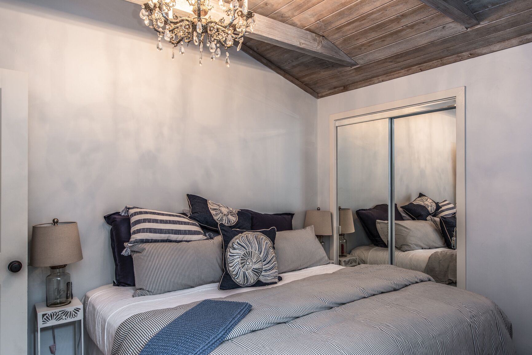 Un dormitorio con cama, espejo y candelabro.