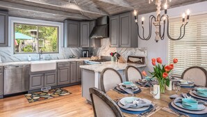 A modern kitchen with grey cabinets, a marble countertop, and a dining area set for six with blue and grey tableware.