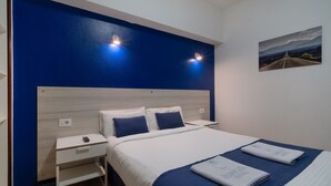 Una habitación de hotel con una cama grande, una mesita de noche y un cuadro en la pared.