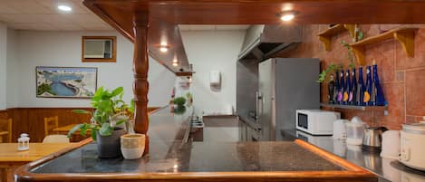 A restaurant with a wooden counter, a painting on the wall, and a microwave on the counter.