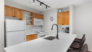 Une cuisine moderne avec des appareils électroménagers blancs, des armoires en bois et un grand îlot central doté d’un évier.
