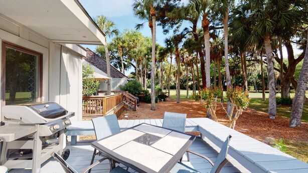 Un patio con barbecue, posti a sedere all'aperto e alte palme.