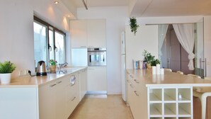 Eine moderne Küche mit weißen Schränken, einem Edelstahlbackofen und einem Fenster mit Vorhängen.