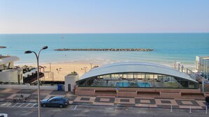 Ein modernes Gebäude mit einer gewölbten Glasfassade mit Blick auf einen Strand.
