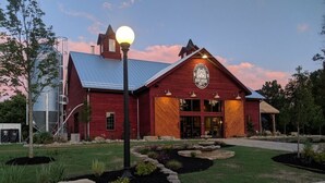 A red building with a large sign, a well-maintained lawn, and a metal silo in the background. - WaterfrontHome-Nature,Views,Peace-up to 12, ideal for Family/Friends/Celebration (Cambridge Springs)