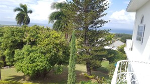 A residential area with a view of the sea, surrounded by lush greenery and a white building with a balcony. - 5 Bed Room Villa with Swimming pool  (Montego Bay)