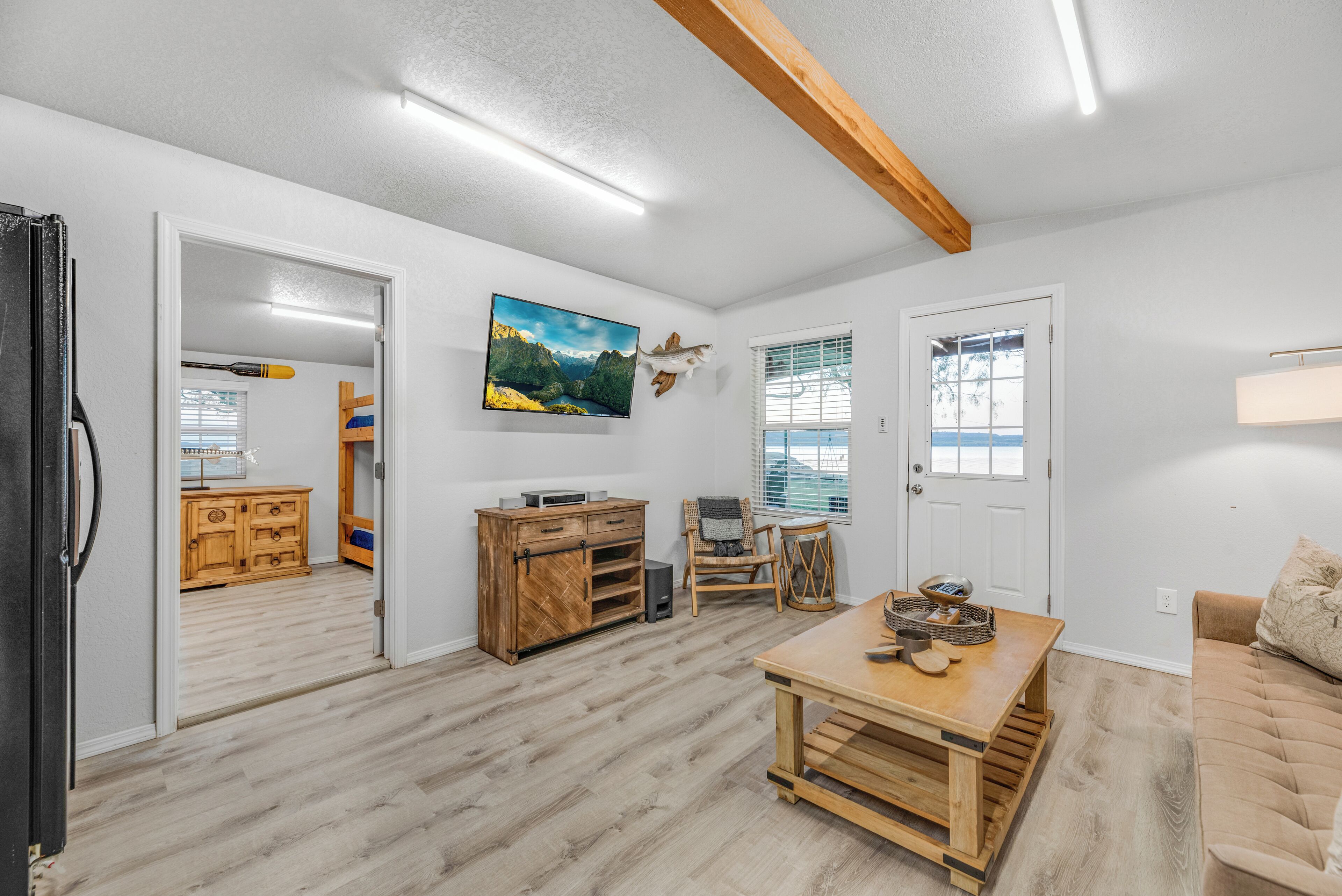 Een ruime woonkamer met een houten eettafel, een bank en een keuken op de achtergrond.