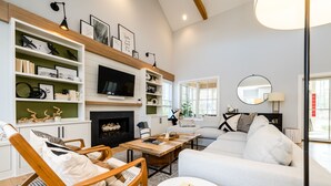 Un salon moderne doté d’une cheminée, d’un téléviseur et d’un coin salon confortable avec un canapé et des fauteuils.
