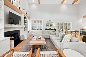 A modern living room with a fireplace, a television, and a dining area with a table and chairs.