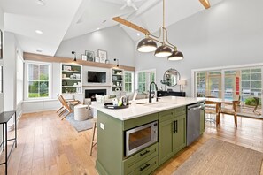 A modern kitchen with a central island, built-in appliances, and a dining area with a view. - 2027 Calendar OPEN! Modern Cottage With Private Pool And Close To Beach! (Union Pier)