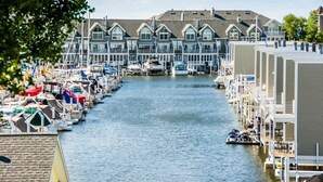 Un port de plaisance où les bateaux sont amarrés le long d’un canal étroit, entouré d’immeubles à plusieurs étages dotés de grandes fenêtres et de balcons.