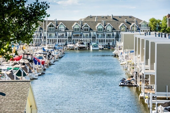 A marina with boats docked along a narrow waterway, surrounded by multi-story buildings with large windows and balconies.