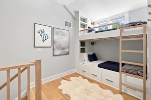A bunk bed room with a white and blue color scheme, wooden flooring, and a white shag rug. - 2027 Calendar OPEN! Modern Cottage With Private Pool And Close To Beach! (Union Pier)