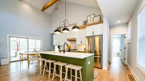 Une cuisine spacieuse dotée d’un grand îlot central, de tabourets en bois et d’appareils électroménagers en acier inoxydable.