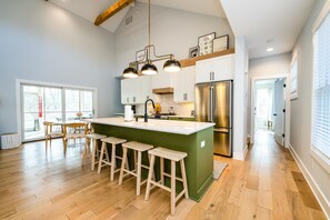 A spacious kitchen with a large island, wooden stools, and stainless steel appliances.