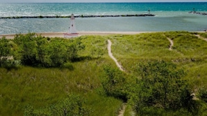 Un phare se dresse sur une plage herbeuse, offrant une vue dégagée sur l’océan.