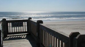 A wooden boardwalk leading to a beach with waves in the background.