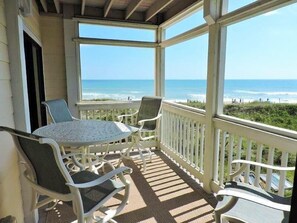 Relax in this oceanfront seating area with a view of the beach, featuring a table and two chairs.