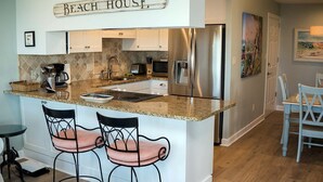 A kitchen with a granite countertop, stainless steel appliances, and a sign reading "Beach House".