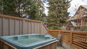 Un bain à remous installé dans une structure en bois, entouré d’une clôture en bois et agrémenté de chaises.