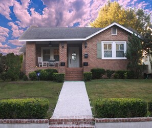 A two-story brick house with a front porch, a mailbox, and a well-maintained lawn.