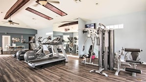 Un gimnasio con cintas de correr, elípticas y equipo de pesas.