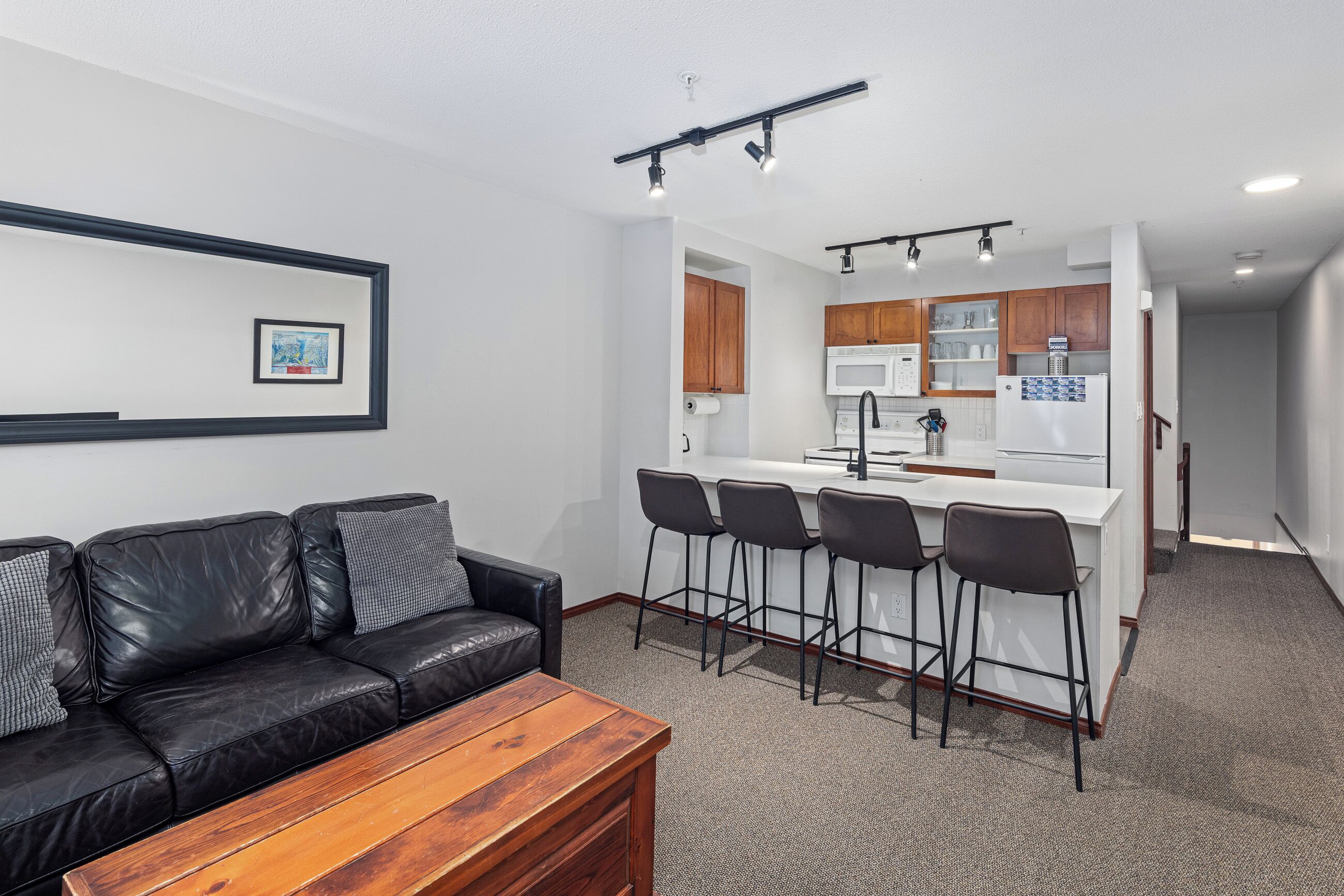 Una cocina moderna con una isla central, taburetes de bar y una mesa de comedor.