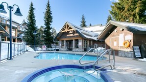 Ein Poolbereich mit Whirlpool und einem Holzgebäude mit Satteldach.