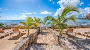 A beachside lounge with stone walls and lounge chairs. - Amazing View Oceanfront with 2 pools, Daily Housekeeping (Akumal)