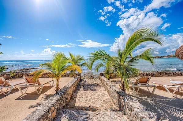 A beachside lounge with stone walls and lounge chairs.