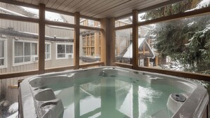 Ein Whirlpool mit Blick auf eine verschneite Landschaft durch große Fenster.