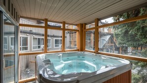 Ein Whirlpool auf einer Holzterrasse mit großen Fenstern mit Blick auf eine Wohngegend.