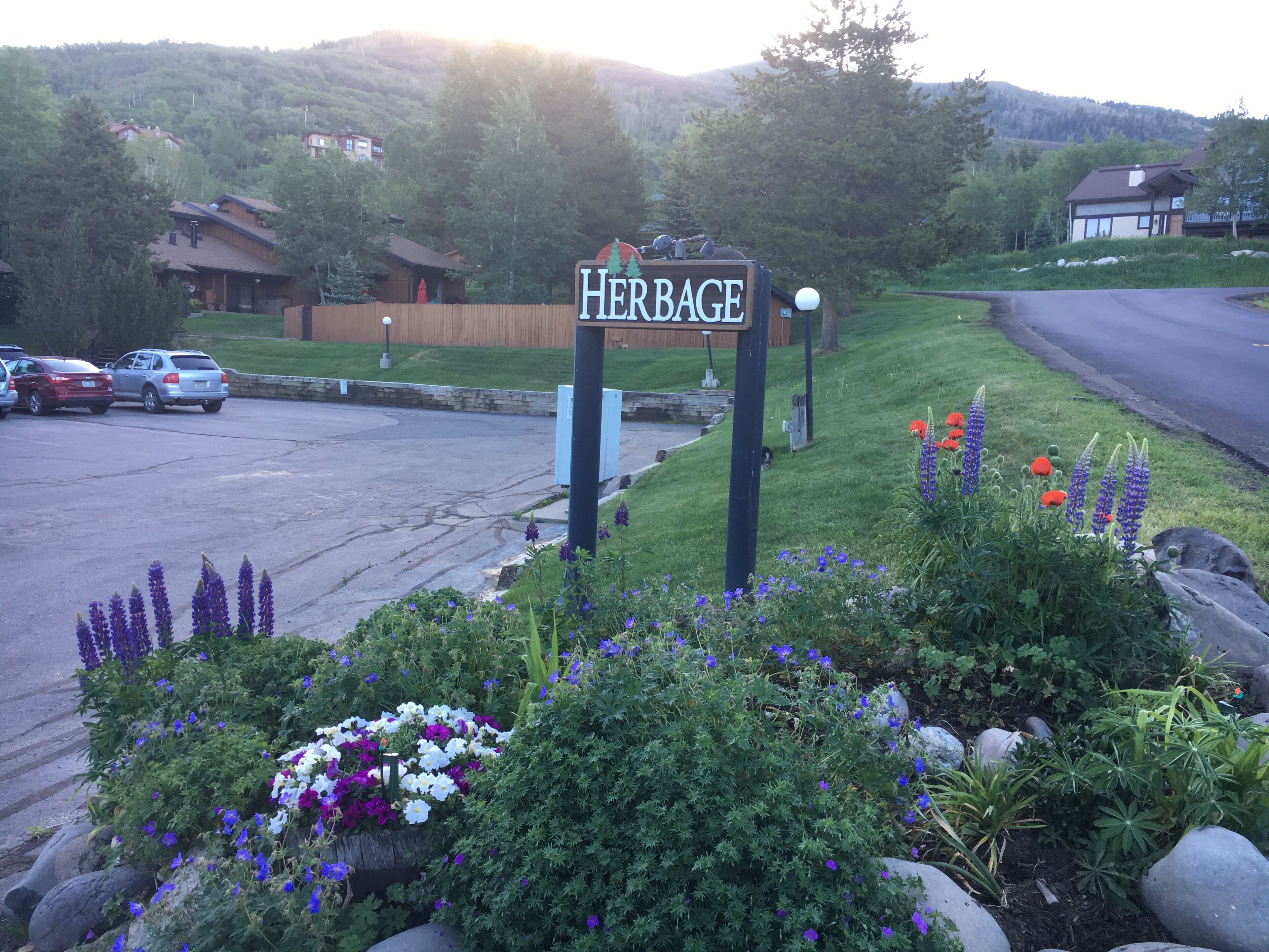 Señal que dice 'Heritage', con un estacionamiento y una zona ajardinada con flores y arbustos.