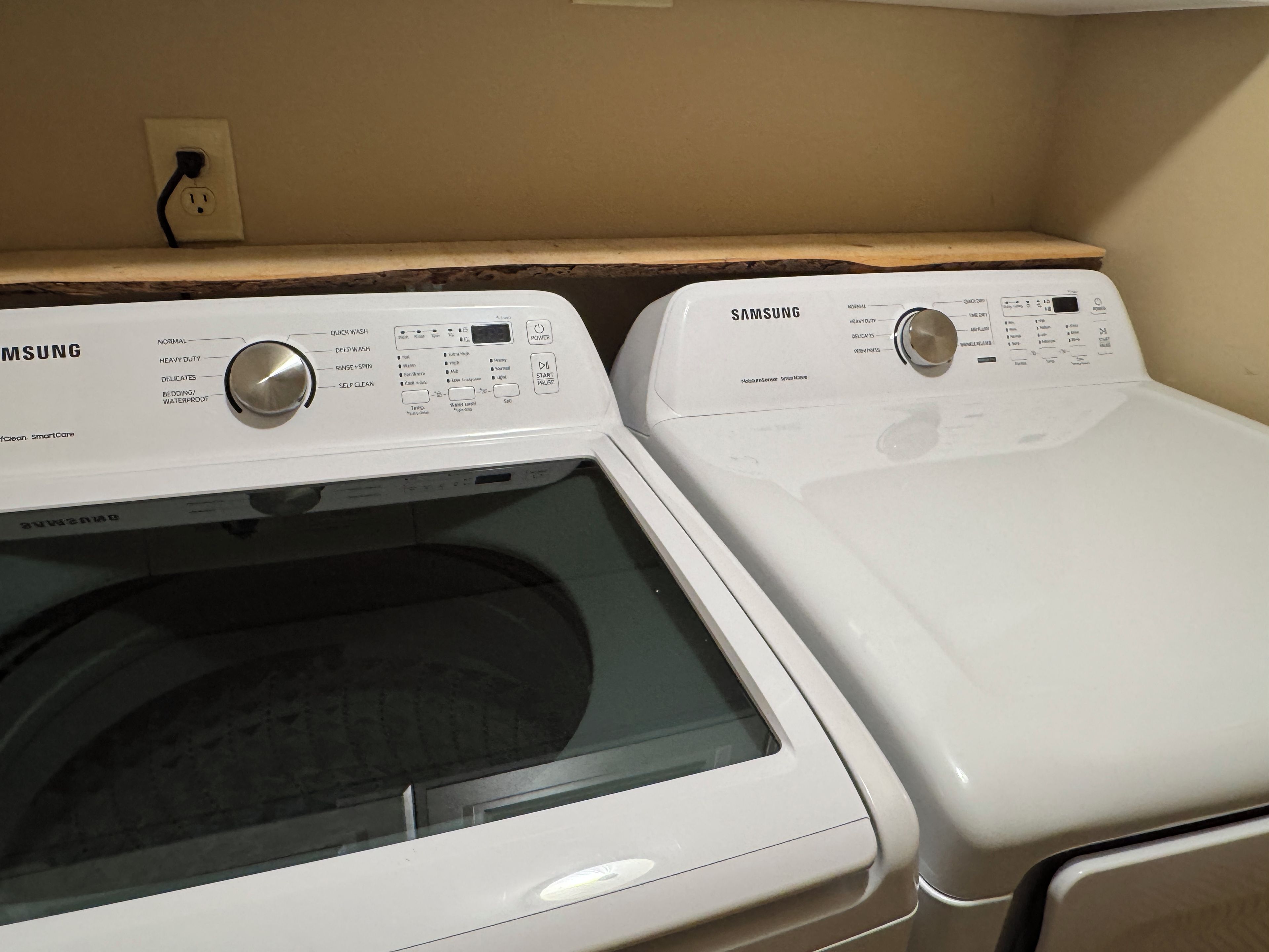 Twee witte Samsung voorladers in een wasserette, met een houten plank erboven.