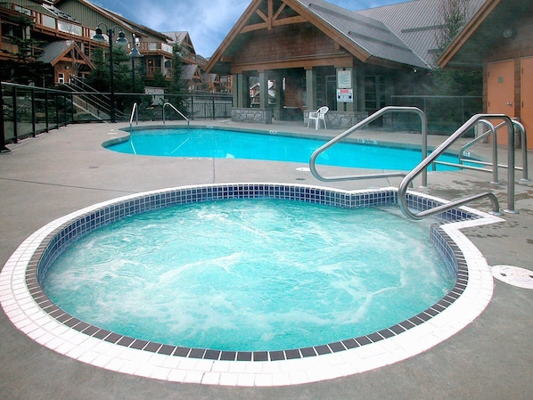 Un bain à remous doté d’un bord carrelé, entouré d’une terrasse en béton.
