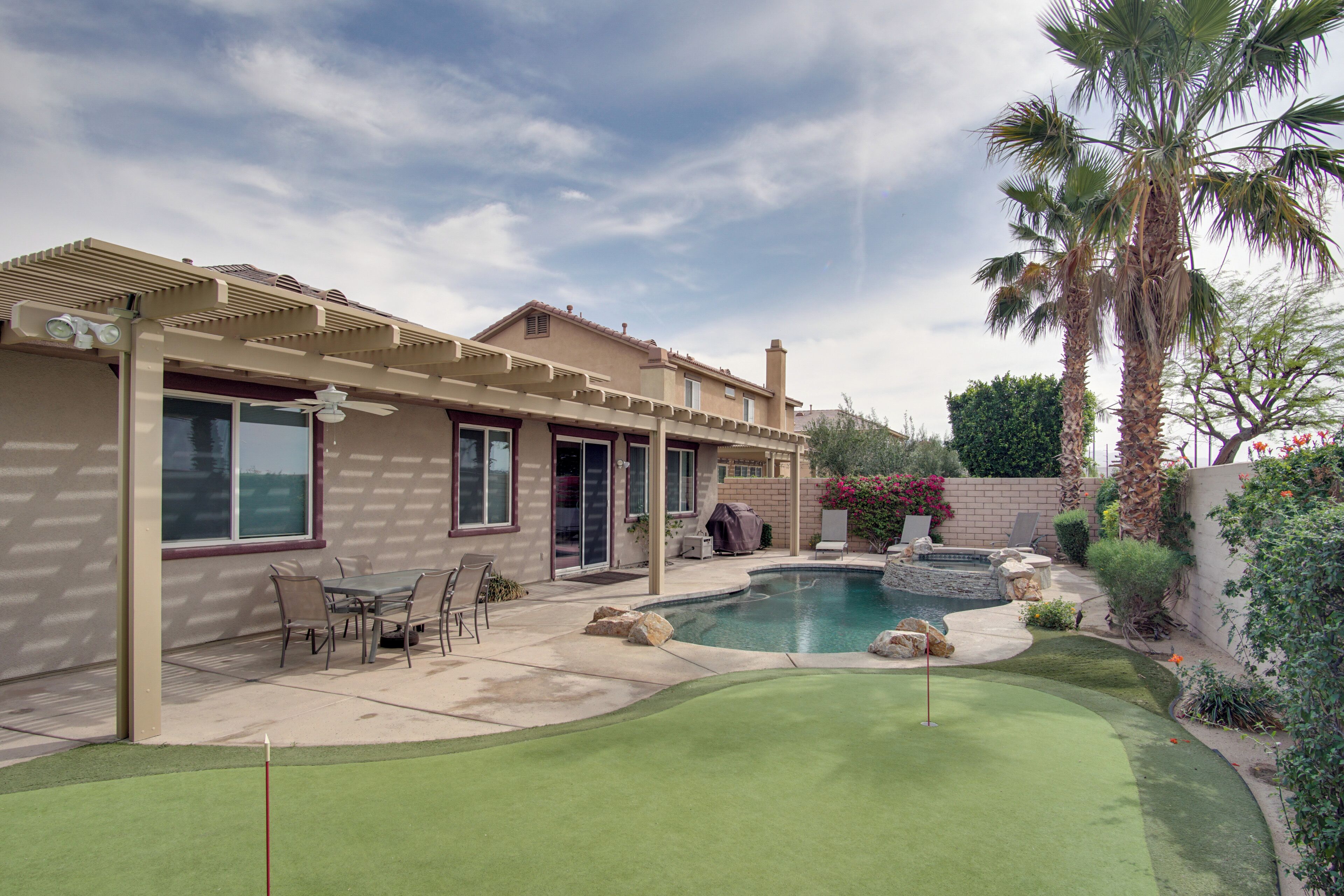 A residential property with a swimming pool, patio furniture, and a well-maintained lawn.